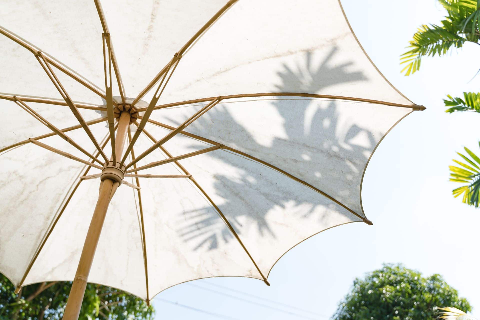 Weißer Sonnenschirm, der von unten betrachtet wird, mit Schatten von Palmen, als stilvolle Ergänzung zu Gartenpavillons und einem gemütlichen Outdoor-Ambiente.