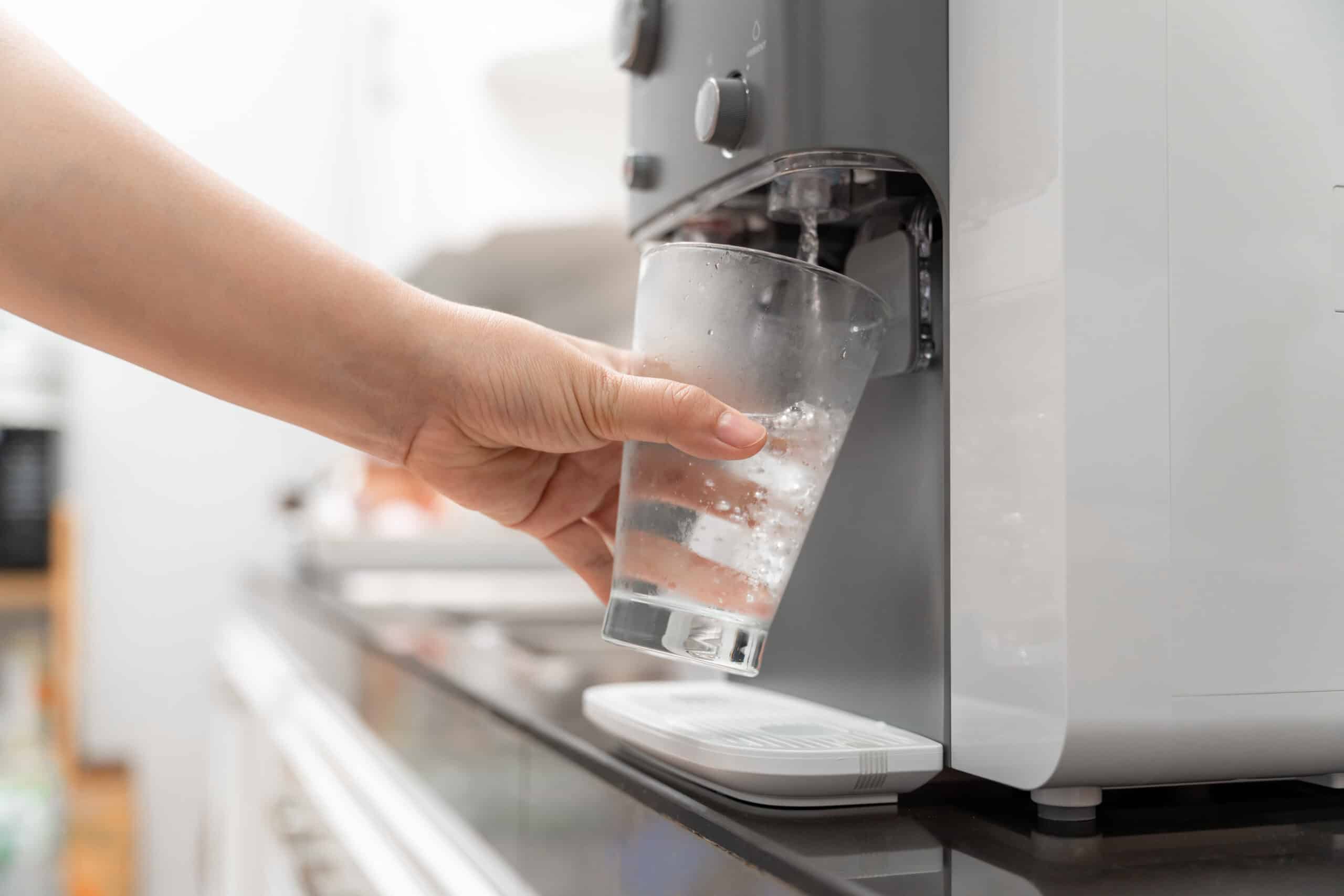 Eine Frau gießt sich Wasser aus einem Wasserfilter ein